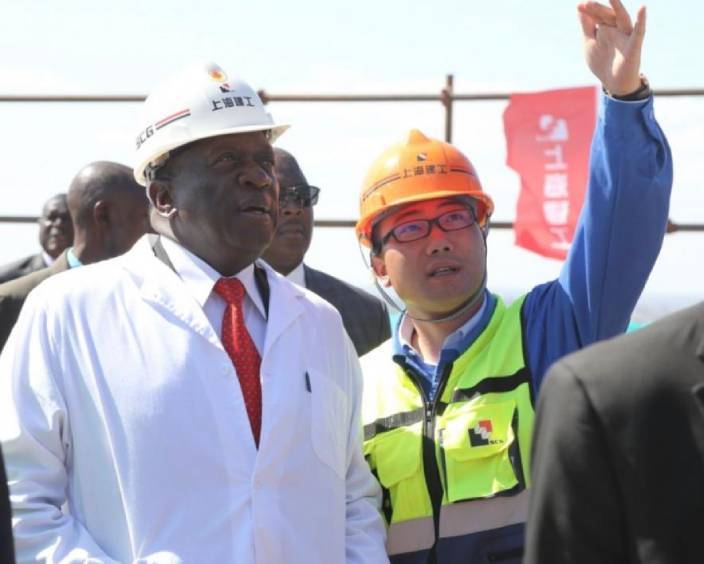 2019年6月13日，在津巴布韋西馬紹納蘭省漢普登山，津巴布韋總統埃默森·姆南加古瓦（前左）在施工方上海建工集團援津巴布韋議會大廈項目經理蔡力波（前右）的陪同下參觀津巴布韋新議會大廈工地。