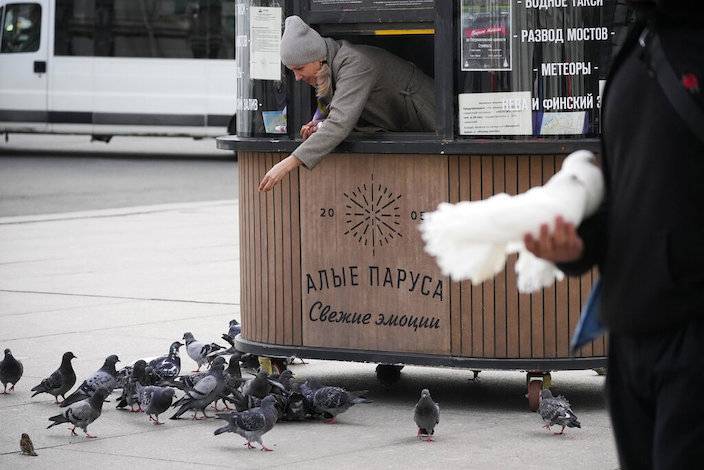 9 月 6 日，一名旅遊售票員在聖彼得堡的攤位上喂鴿子。AP圖片